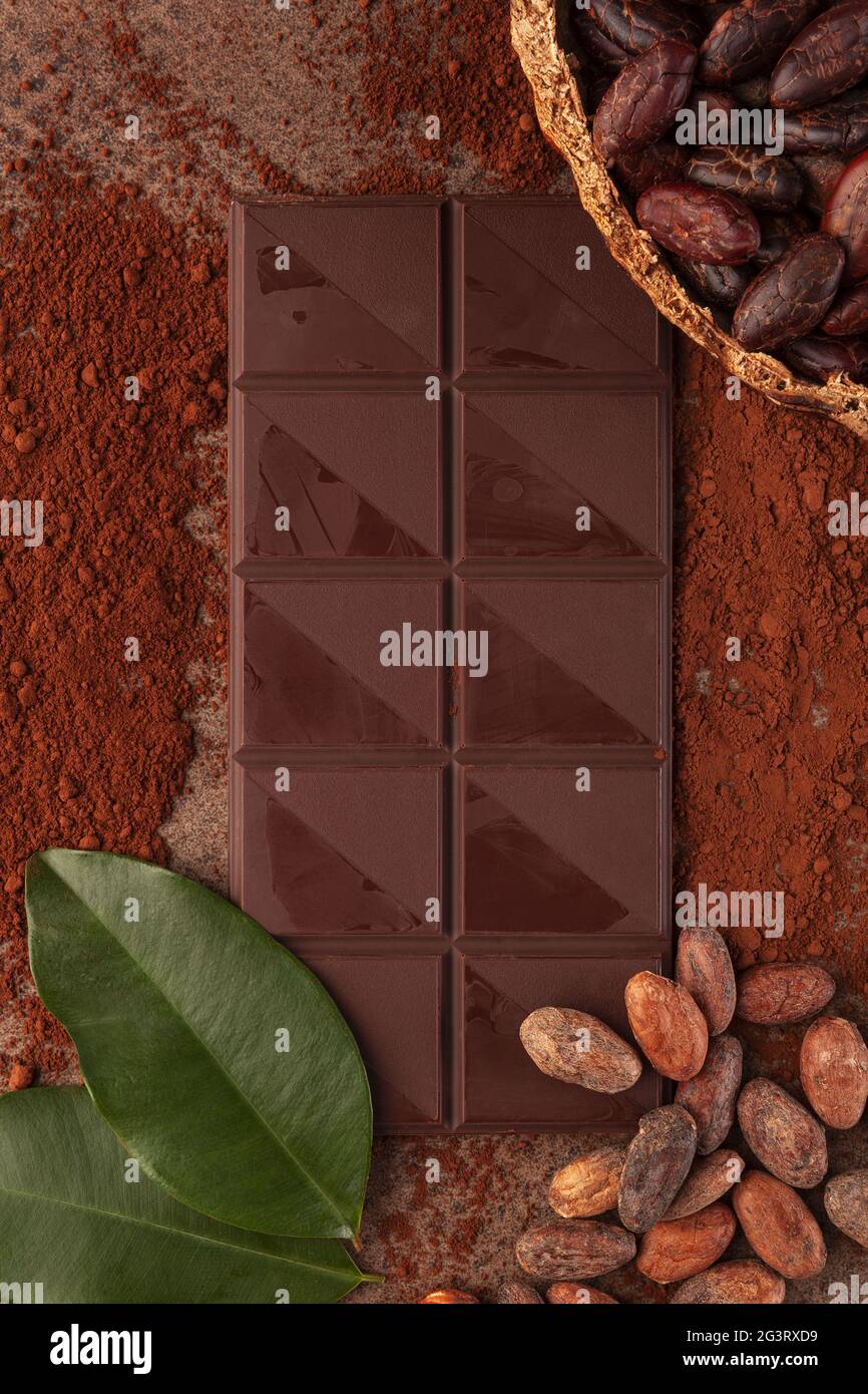 Schokolade, Kakaobohnen und Blätter auf dunklem Hintergrund. Stockfoto