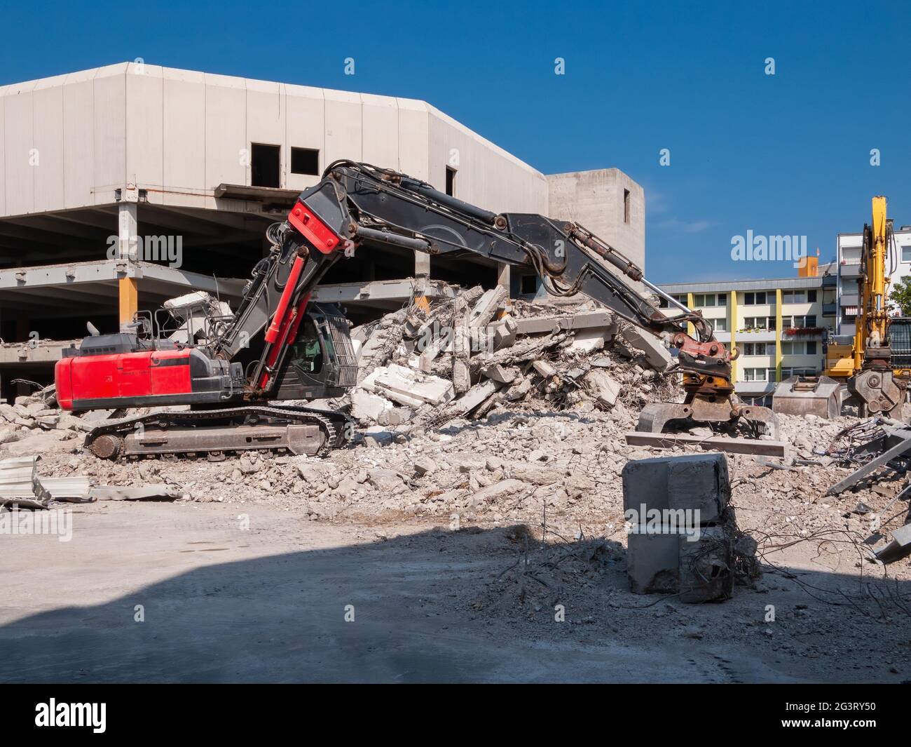 Roter Abbruchbagger mit Greifer vor dem Abbruchgebäude Stockfoto