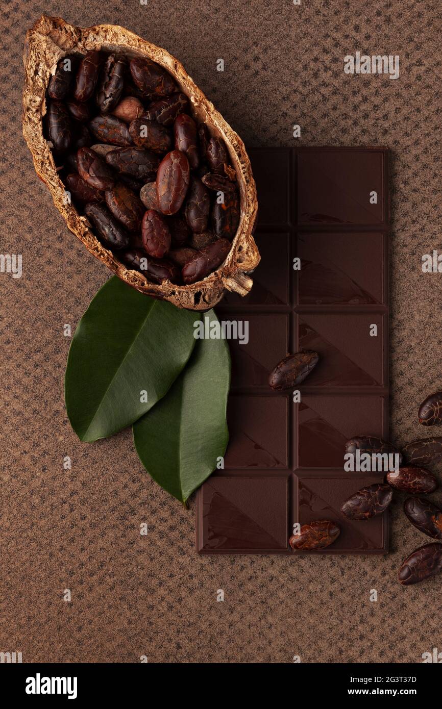 Schokolade, Kakaobohnen und Blätter auf dunklem Hintergrund. Stockfoto