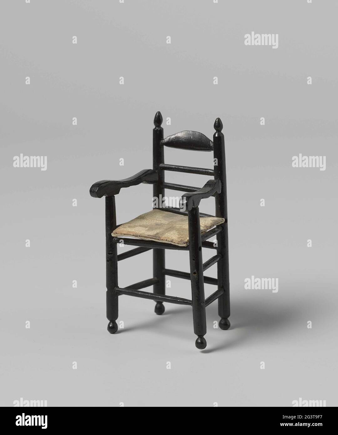 Hochstuhl, schwarz lackiert, mit „Paspelierung“-Sitz. Hoher Kinderstuhl mit  Knöpfen aus schwarz lackiertem Holz mit glatten Drehstilen und Kreuzregeln.  Die obere Rückenlehne ist geschnitten und die Armlehnen sind verklebt. Die  Fußstütze fehlt. Der