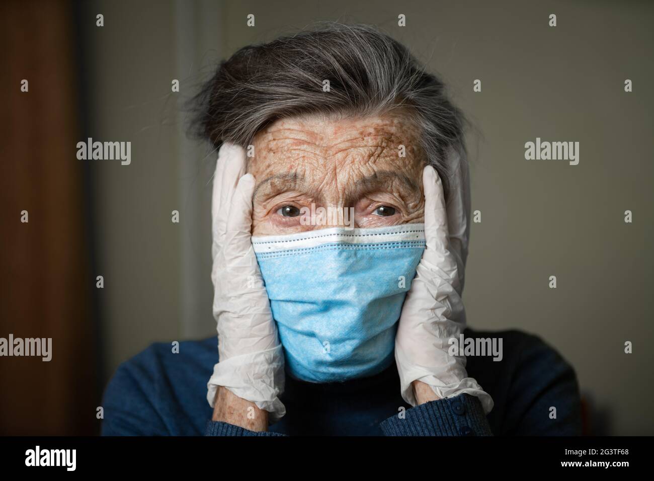 Porträt einer älteren kaukasischen Frau mit Falten, das Tragen einer medizinischen Maske und Handschuhe, die Emotion des Schreckens und unpredictabily Stockfoto