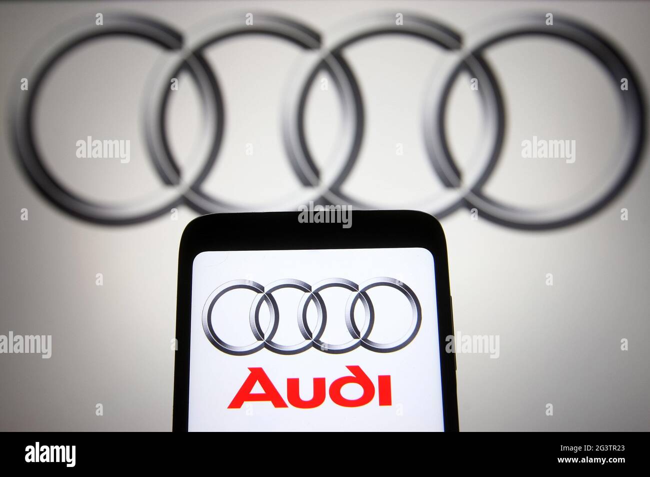In dieser Abbildung ist das Audi Logo eines deutschen Automobilherstellers auf einem Smartphone und einem pc-Bildschirm im Hintergrund zu sehen. Stockfoto