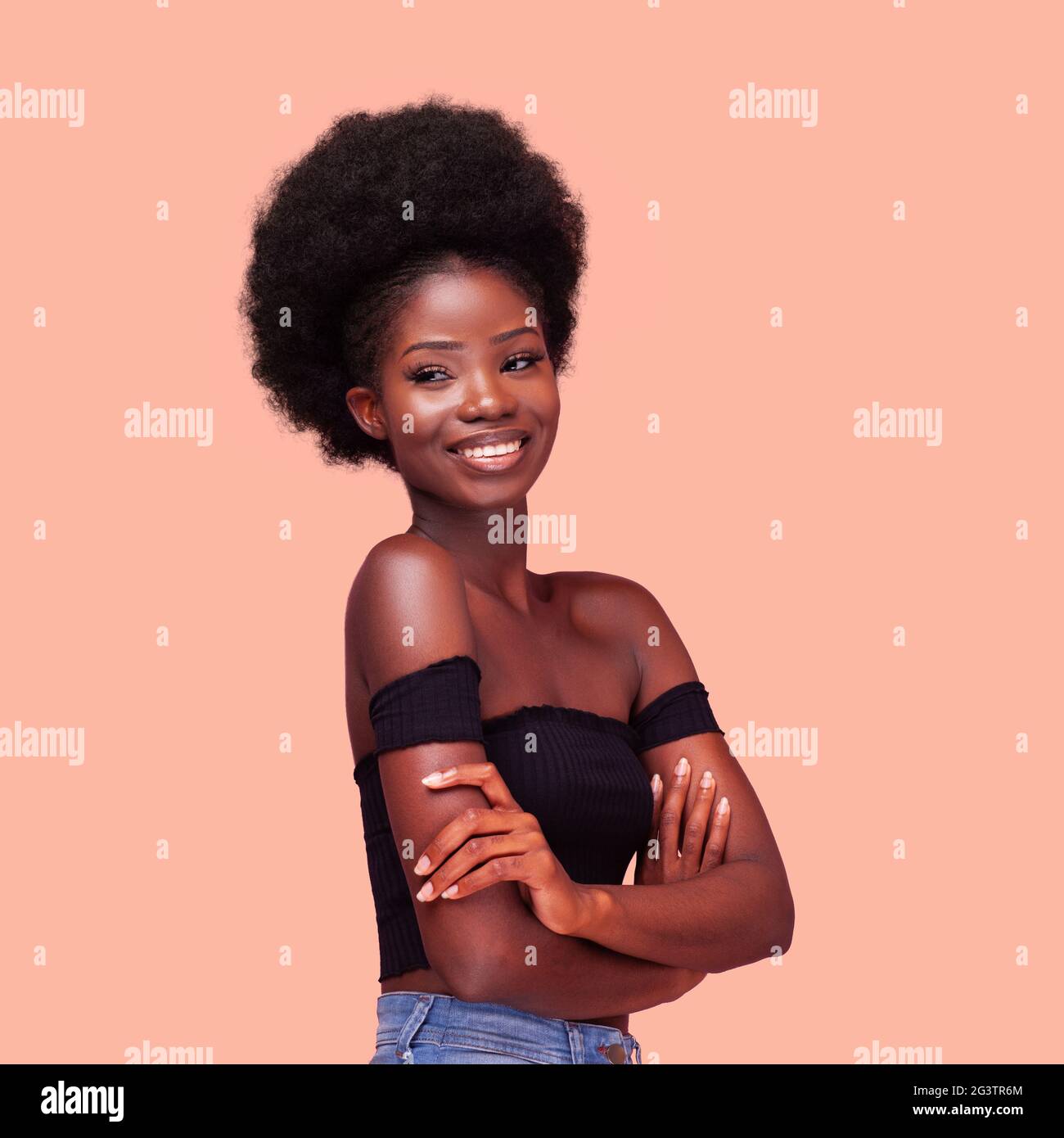 Quadratisches Porträt von glücklichen charmanten afroamerikanischen Mädchen mit erstaunlichen afro Frisur lächelnd mit Armen gefaltet. Dunkelhäutige Dame Stockfoto