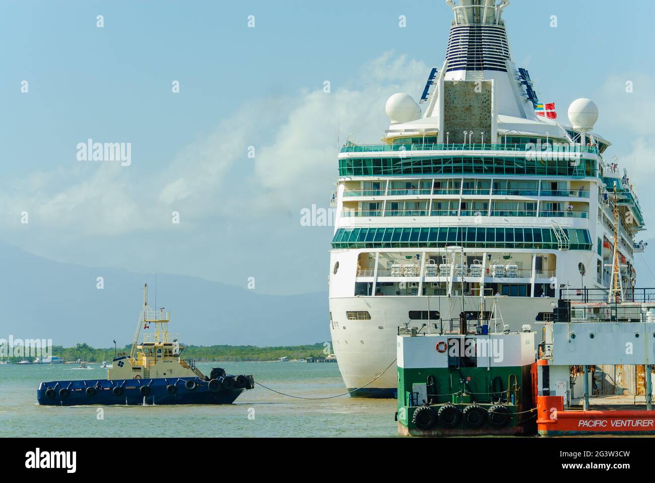 Der Kreuzfahrtliner Rhapsody of the Seas kommt in Ports North in Cairns, Queensland, Australien an und wird von einem Schlepper begleitet. Stockfoto
