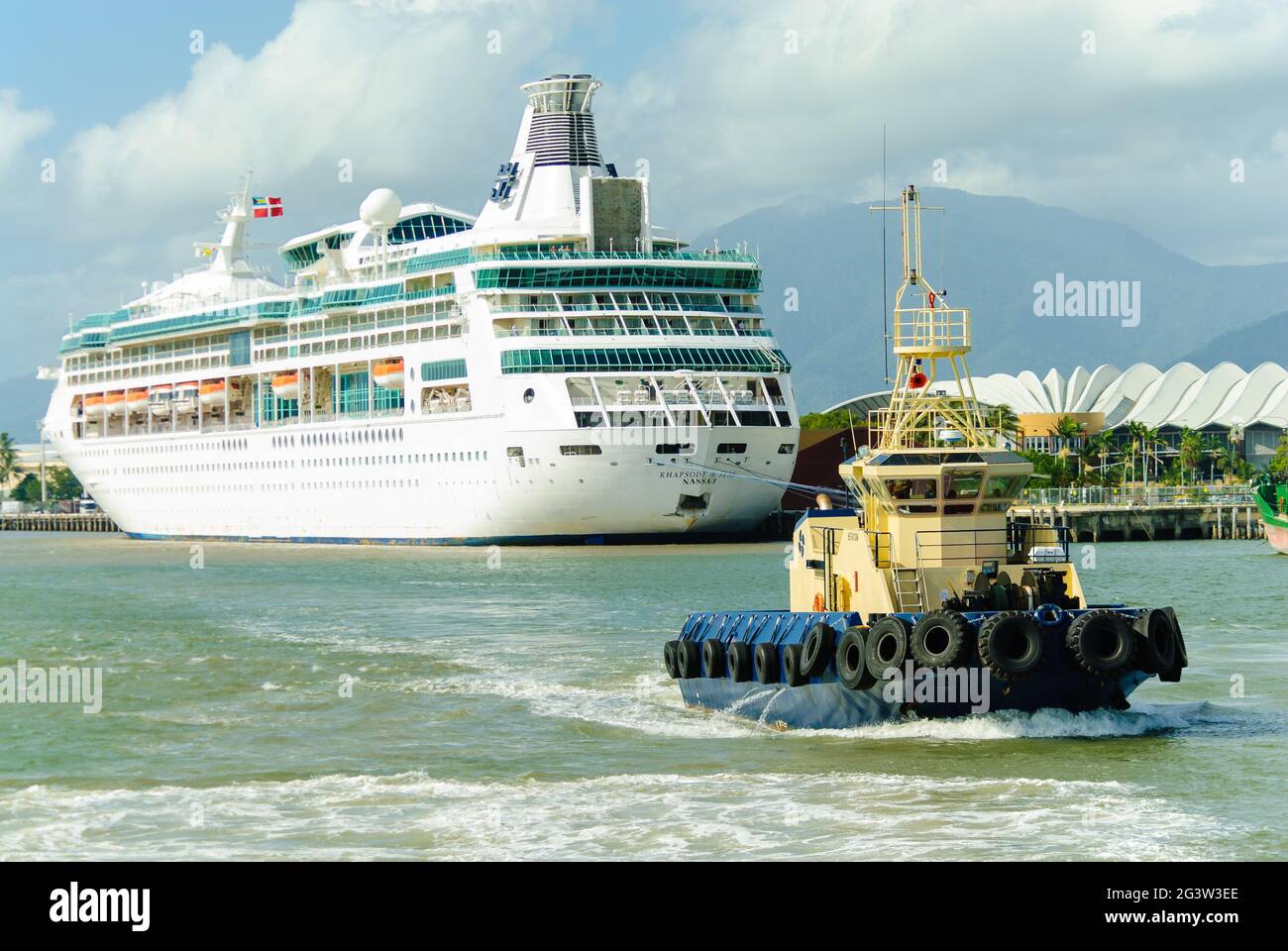 Der Kreuzfahrtliner Rhapsody of the Seas kommt in Ports North in Cairns, Queensland, Australien an und wird von einem Schlepper begleitet. Stockfoto