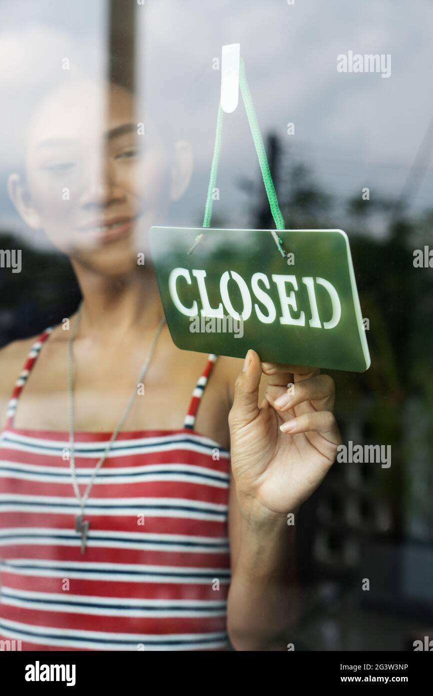 Frau dreht das geschlossene Schild ihres Ladens um Stockfoto