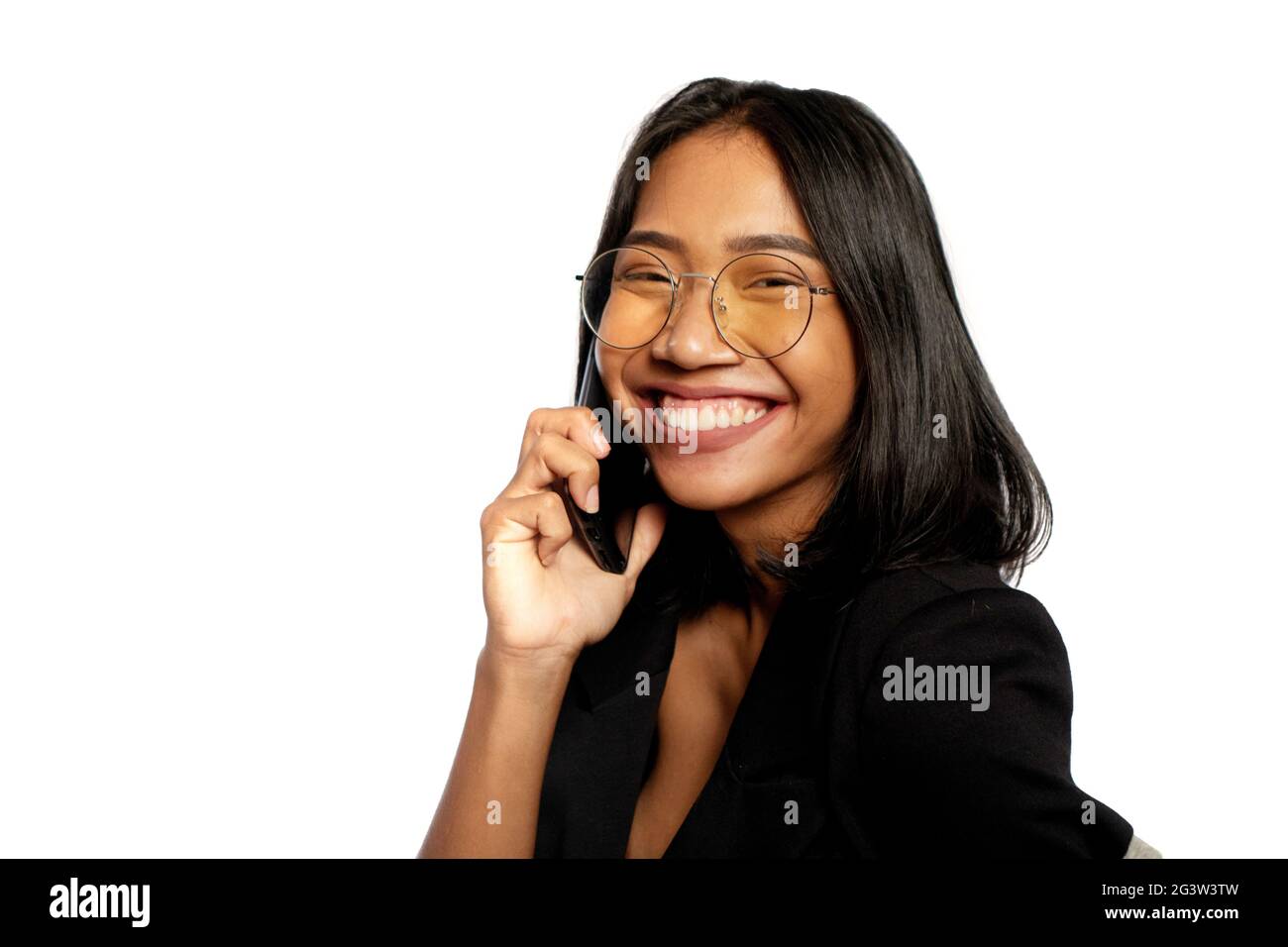 Attraktive junge asiatische Geschäftsfrau, die lächelt, während sie auf einem Mobiltelefon spricht, das isoliert über einer hellgrauen Wand liegt Stockfoto