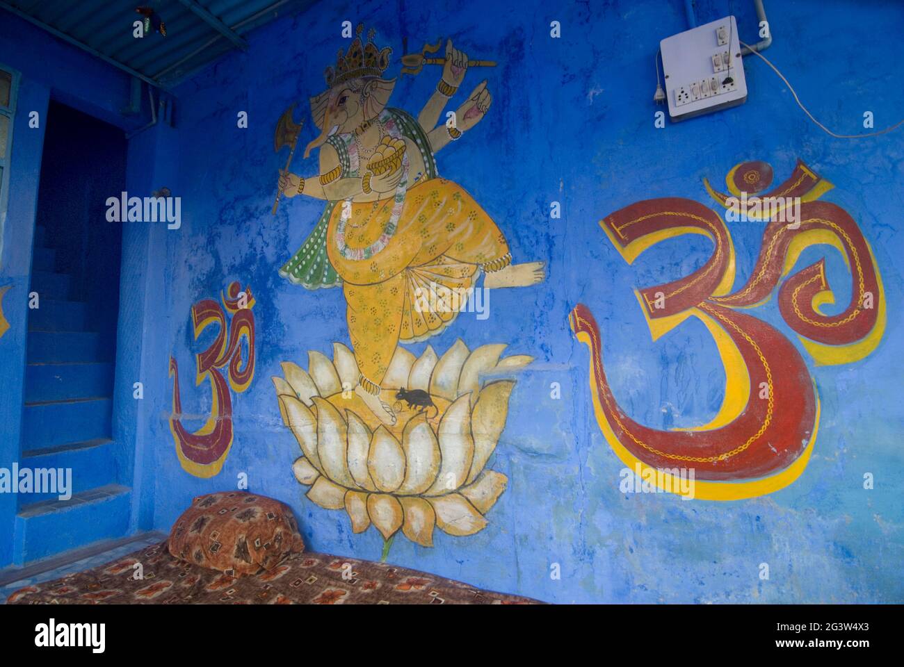 Religiöse Motive, darunter ein Tanzender Ganesh und das Om-Zeichen an der blauen Wand eines Hauses in der blauen Stadt Jodhpur, Rajasthan, Indien Stockfoto