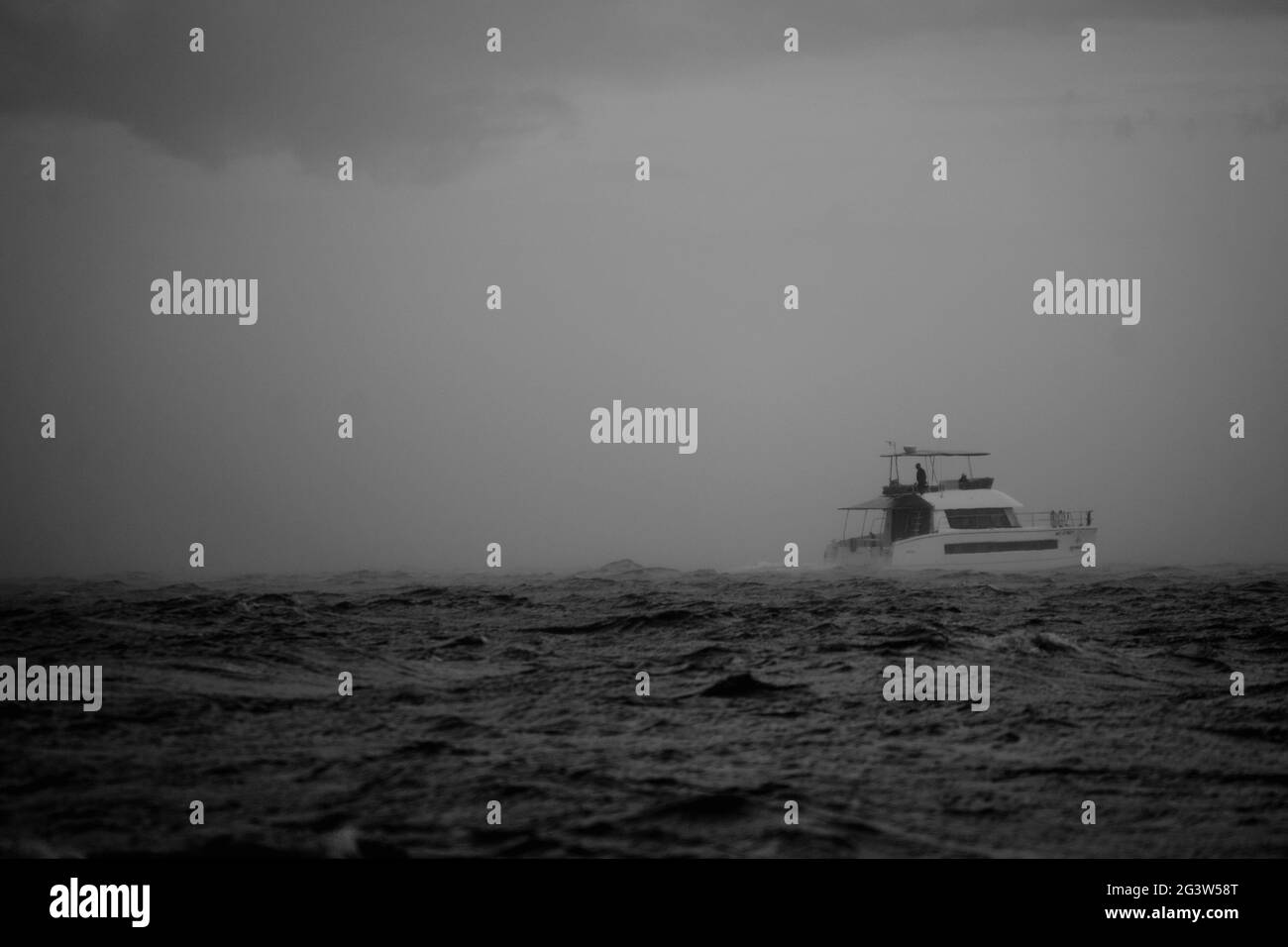 Graustufenaufnahme eines Bootes auf rauer See während eines nebligen Tages Stockfoto