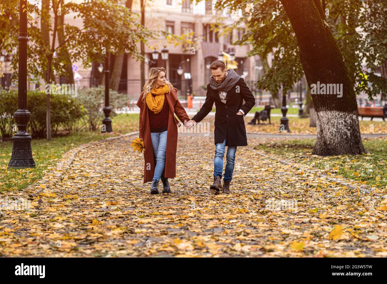 Paar, das im Park läuft und Hände hält. Außenaufnahme eines verliebten jungen Paares, das auf einem Pfad durch einen Herbstpark läuft. Aut Stockfoto