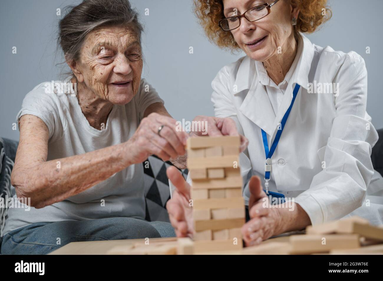 Demenztherapie auf spielerische Weise, Training Finger und Feinmotorik, bauen Holzblöcke in Turm, spielen Jenga. Senior w Stockfoto