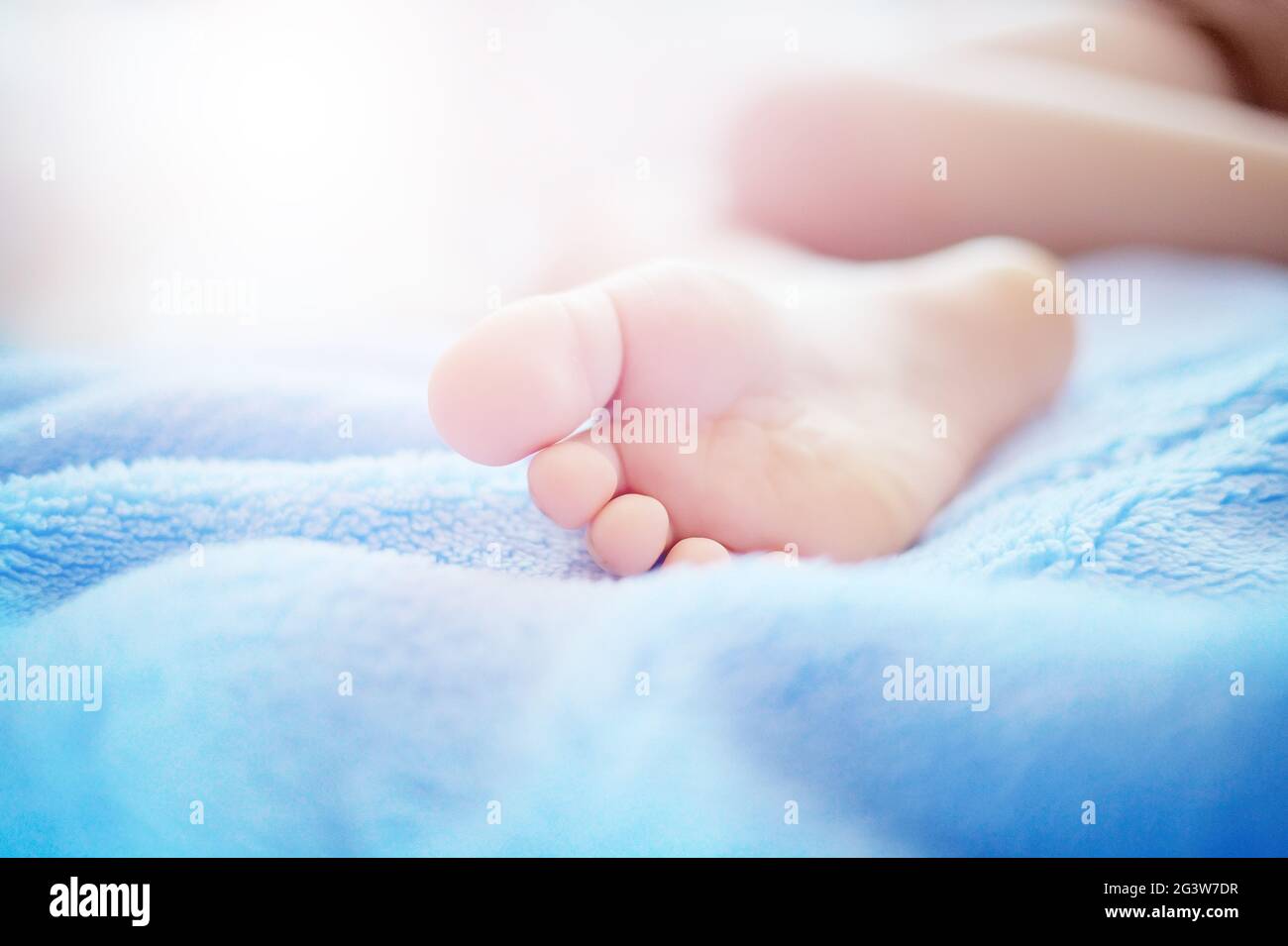 Ein Kinderfuß auf einer weichen blauen Decke Nahaufnahme. Das Konzept der Zärtlichkeit, gesunden Schlaf oder Baby Körperpflege. Stockfoto