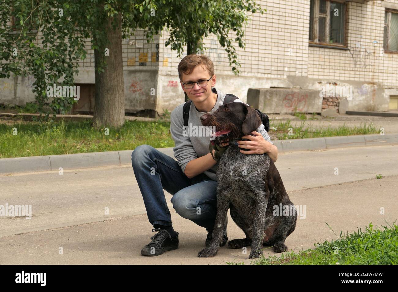 Ein junger Mann mit europäischem Auftritt und einem Hund auf der Straße in der Stadt. Stockfoto