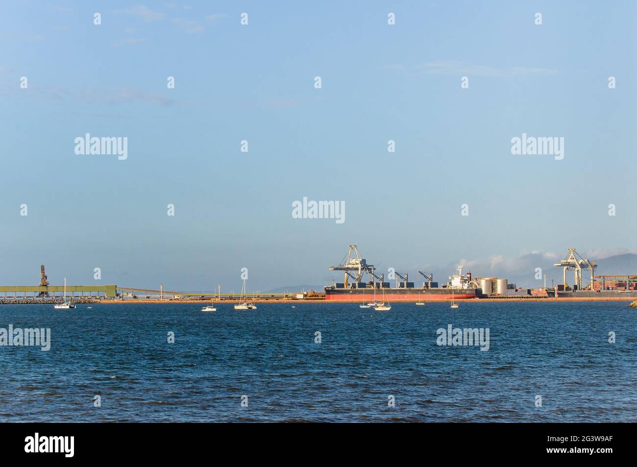Ein aufgeräumter Blick auf den Horizont des Hafens von Townsville in Australien mit einem geburten und beladenen Massengutfrachter, der auf den Abflug wartet. Stockfoto