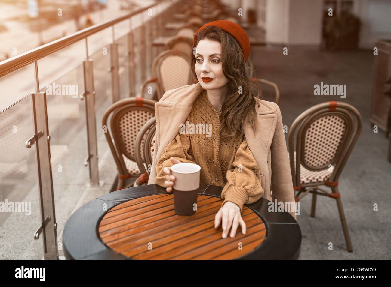 Alles nachdenklich in Erinnerungen junge Pariser Frau sitzt im Freien Restaurant Terrasse Blick weg hält einen Kaffeebecher. Hochformat Stockfoto