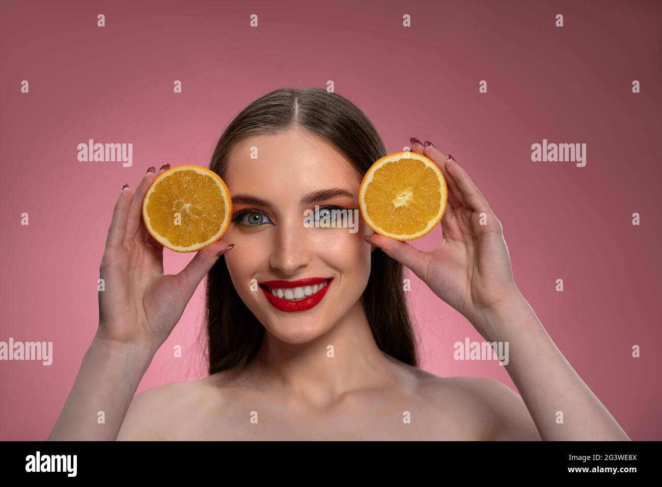 Porträt einer positiven jungen Frau mit Orangen in den Händen geschnitten und charmant. Charmante fröhliche lustige Dame mit langen Haaren Stockfoto