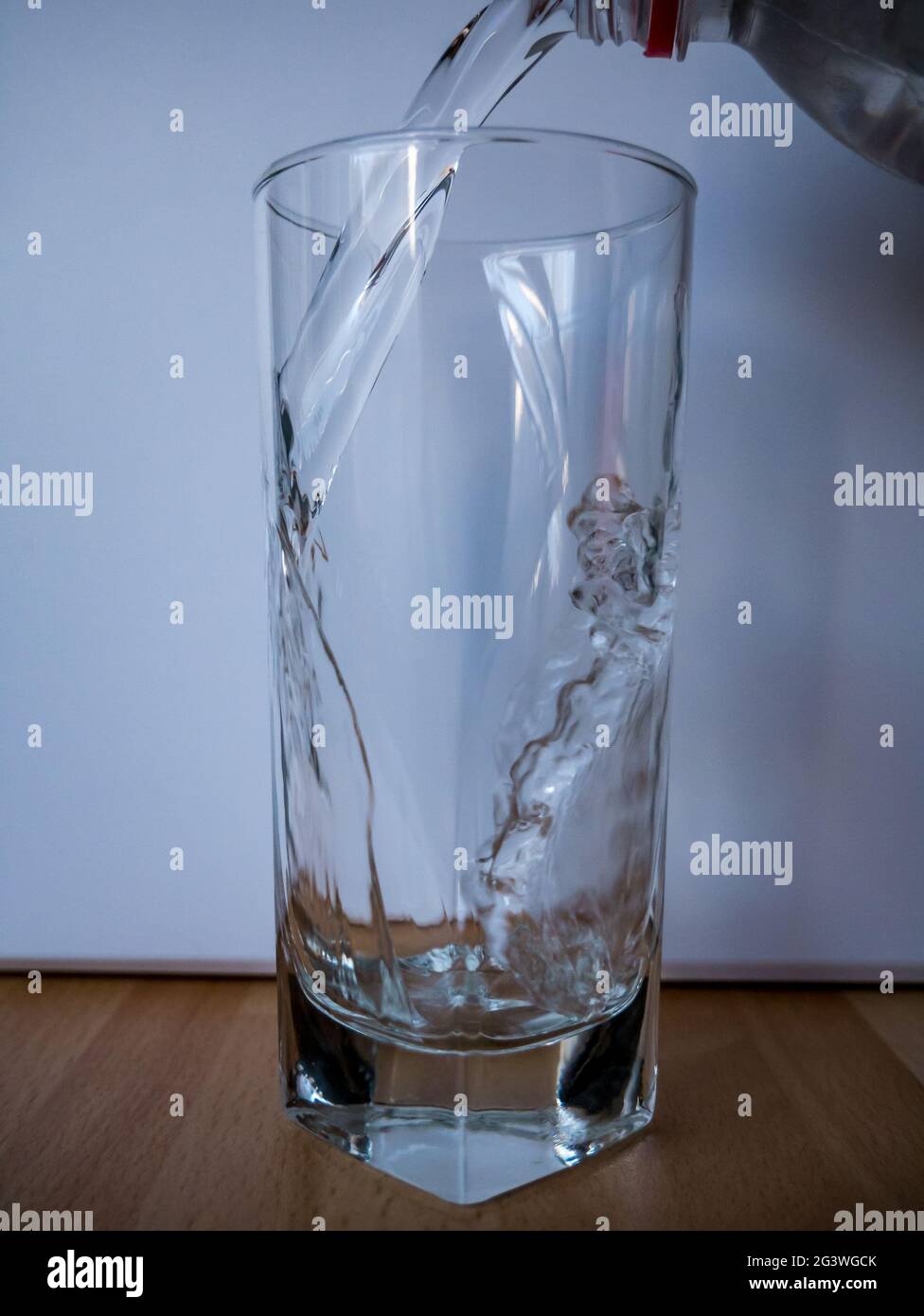 Wasser mit sichtbarem Flaschenhals in das Glas gießen - Bewegung des  gefrorenen Wassers Stockfotografie - Alamy