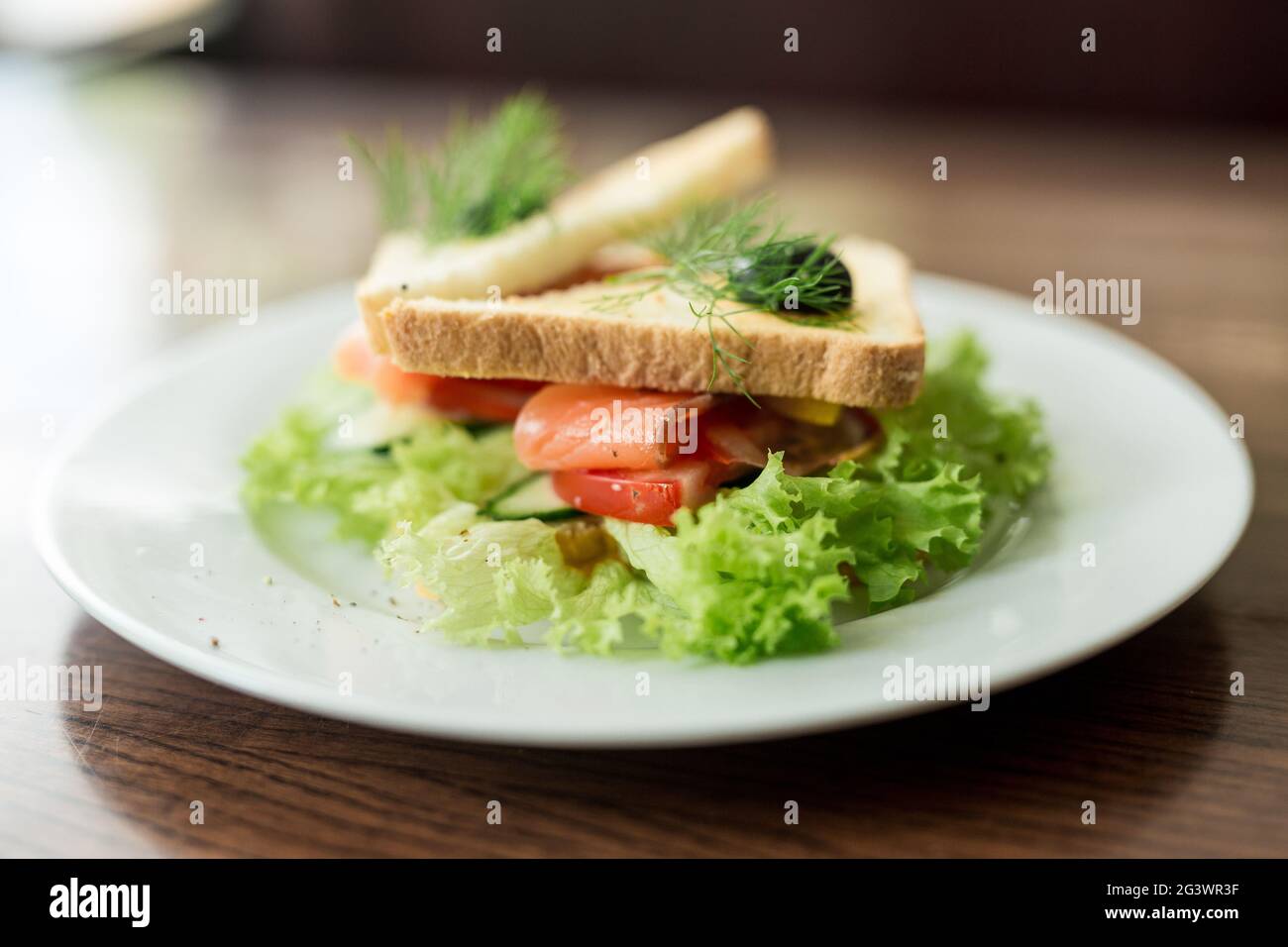 Frühstückssandwich mit Fisch, Lachs und Käse auf frischen Salatblättern. Gerösteter Toast mit Meeresfrüchten und Oliven. Stockfoto