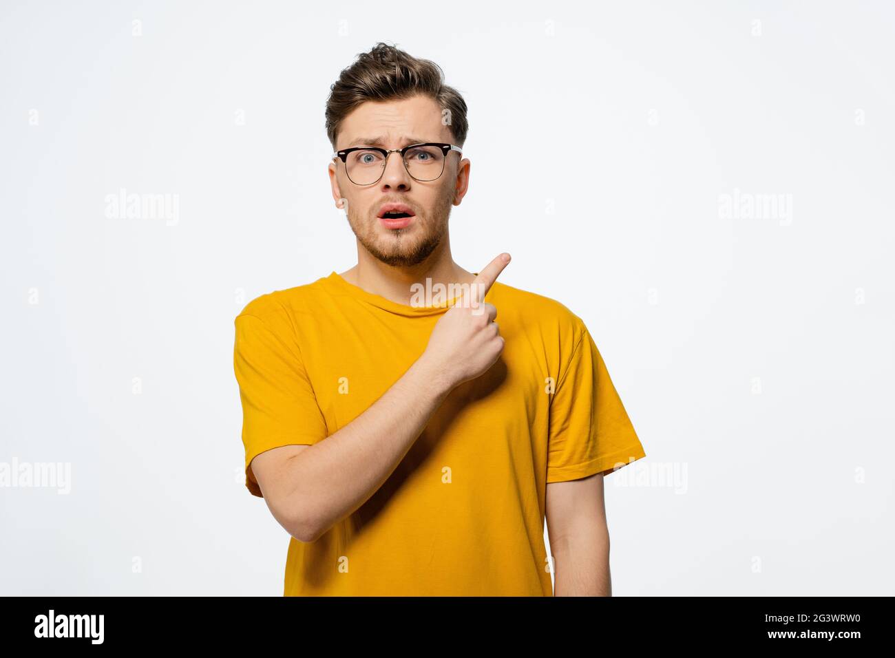 Zeigt nach oben auf einen freien Kopiebereich hübscher junger Mann in einer Brille, schockiert mit überraschender Gesichtsausdruck auf seinem Gesicht Stockfoto