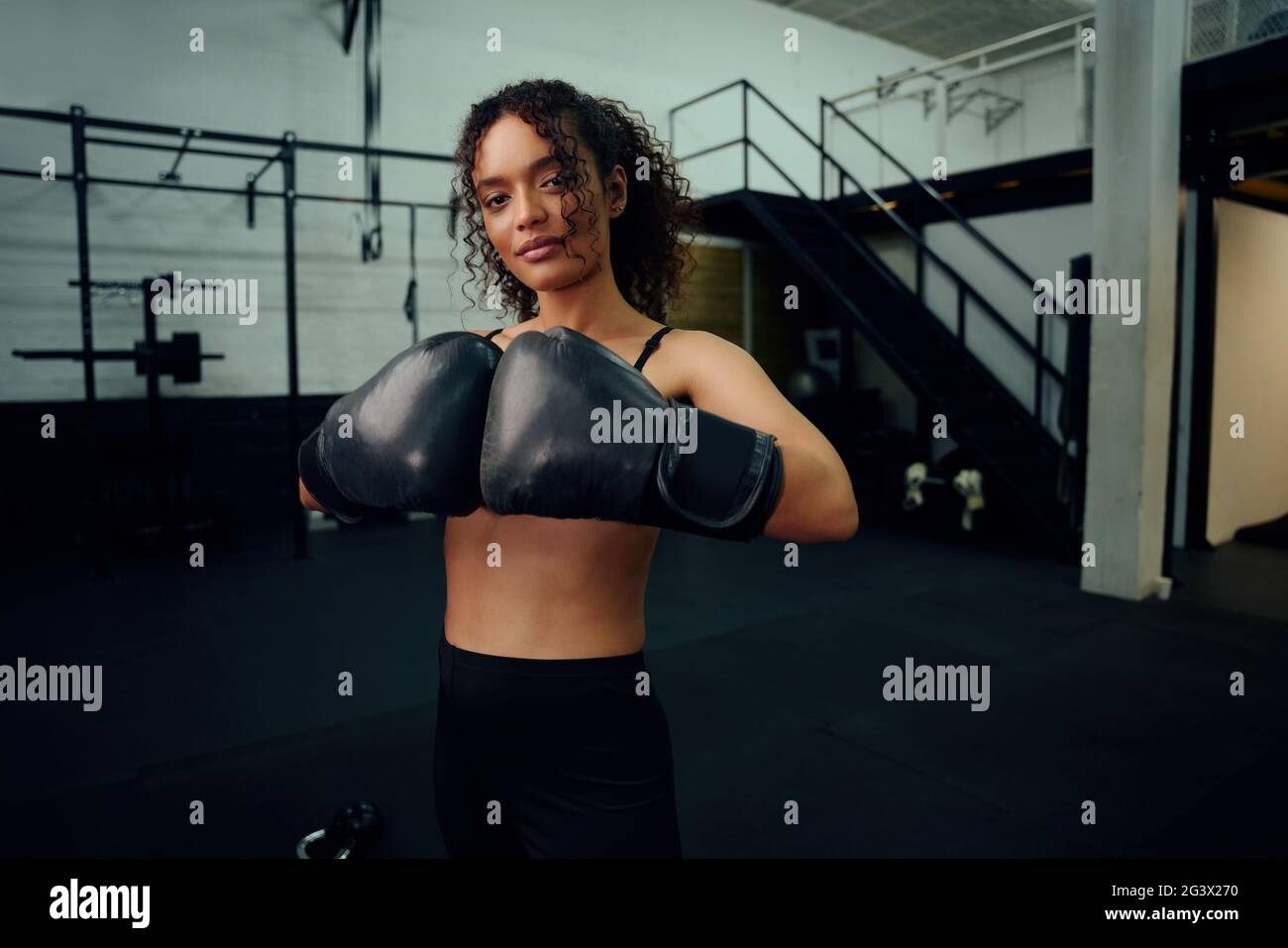 Afroamerikanische Boxerin trainiert im Fitnessstudio mit Boxhandschuhen. Mischfrauin mit Boxhandschuhen in der Luft. Hochwertige Fotos Stockfoto