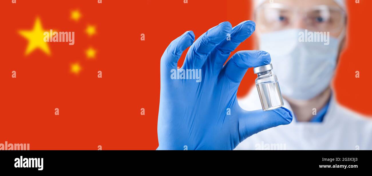Arzt, der eine Viol mit Impfstoff gegen das Corona-Virus hält. Chinesische Flagge auf dem Hintergrund. Stockfoto