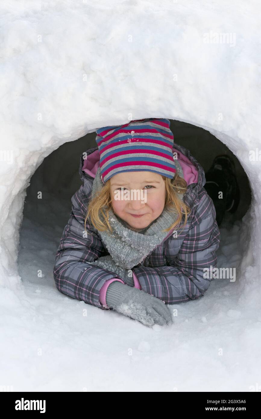 Mädchen, das aus einer Schneehöhle schaut, vertikales Format Stockfoto