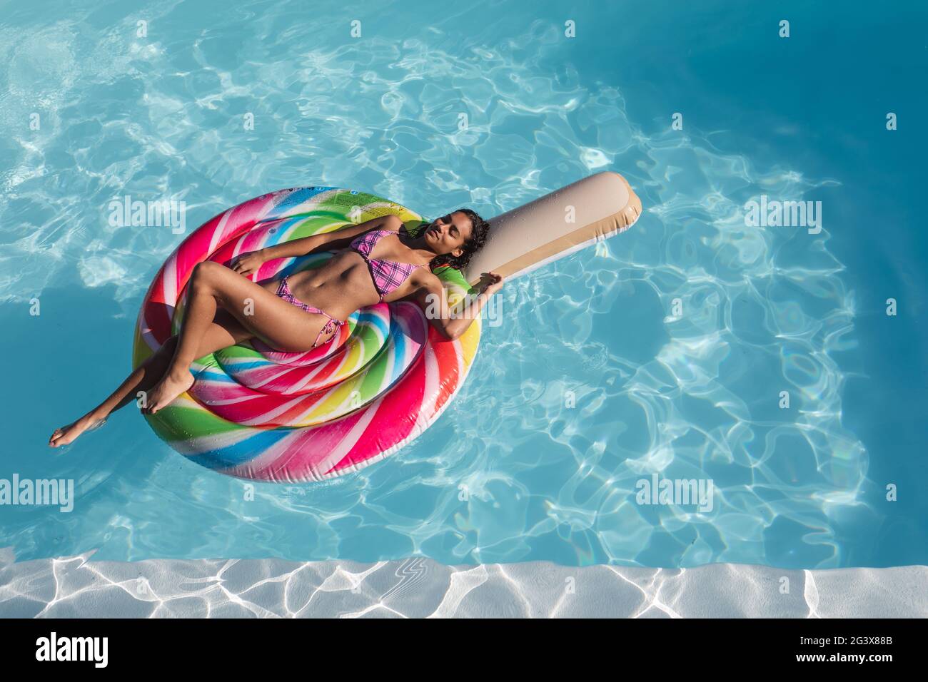 Mixed Race Frau Sonnenbaden auf aufblasbaren im Schwimmbad Stockfoto