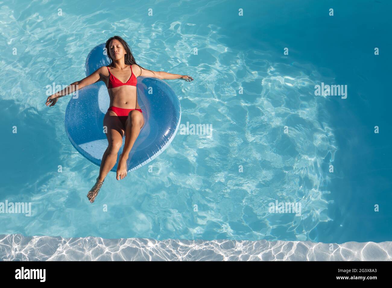 Mixed Race Frau Sonnenbaden auf aufblasbaren im Schwimmbad Stockfoto