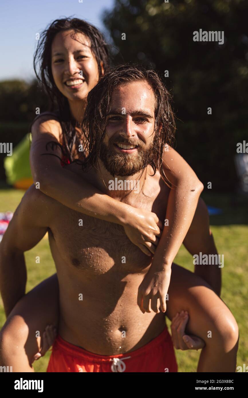 Porträt von zwei verschiedenen männlichen und weiblichen Freunden Mann auf dem Rücken und lächelnd Stockfoto