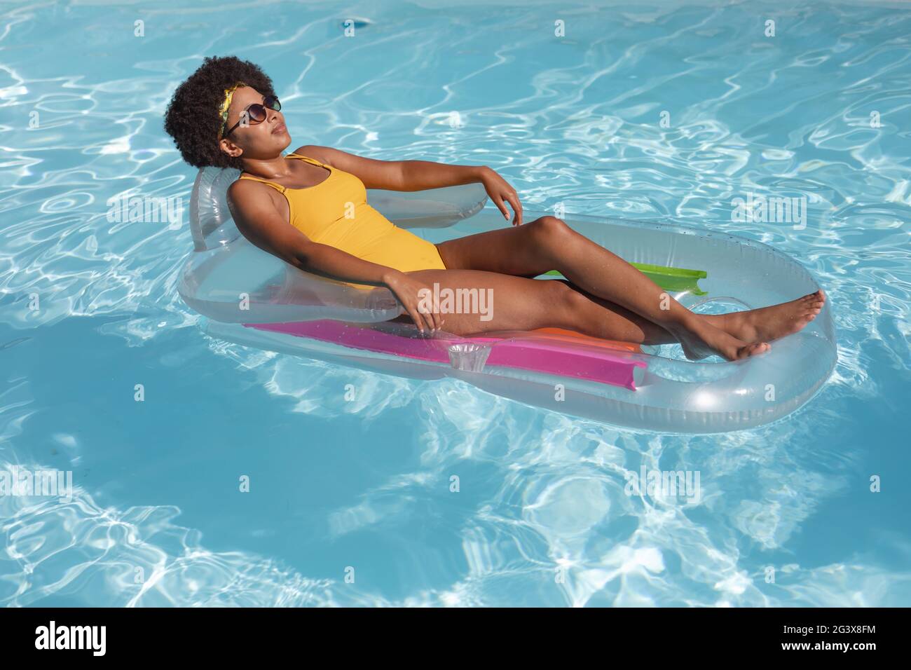 Mixed Race Frau Sonnenbaden auf aufblasbaren im Schwimmbad Stockfoto