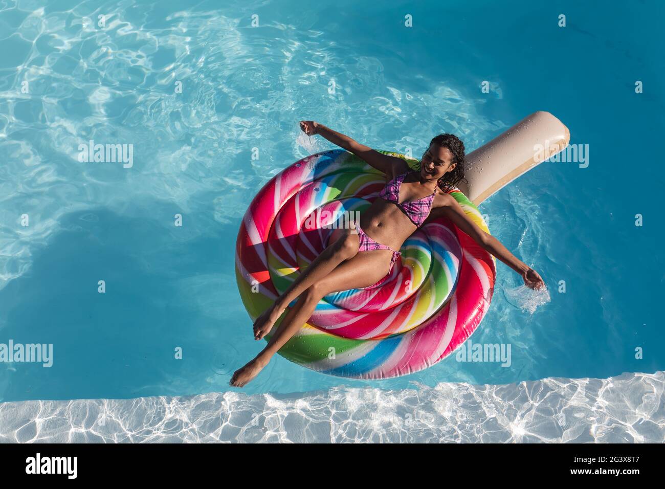 Mixed Race Frau Sonnenbaden auf aufblasbaren im Schwimmbad Stockfoto