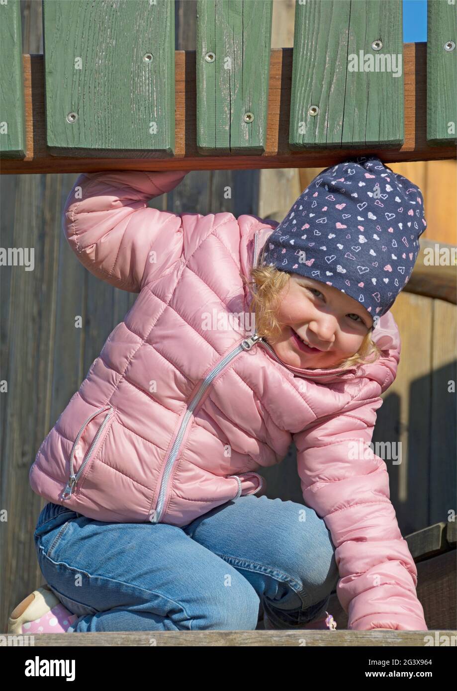 Kleinkind spielt auf Holzkletterrahmen Stockfoto