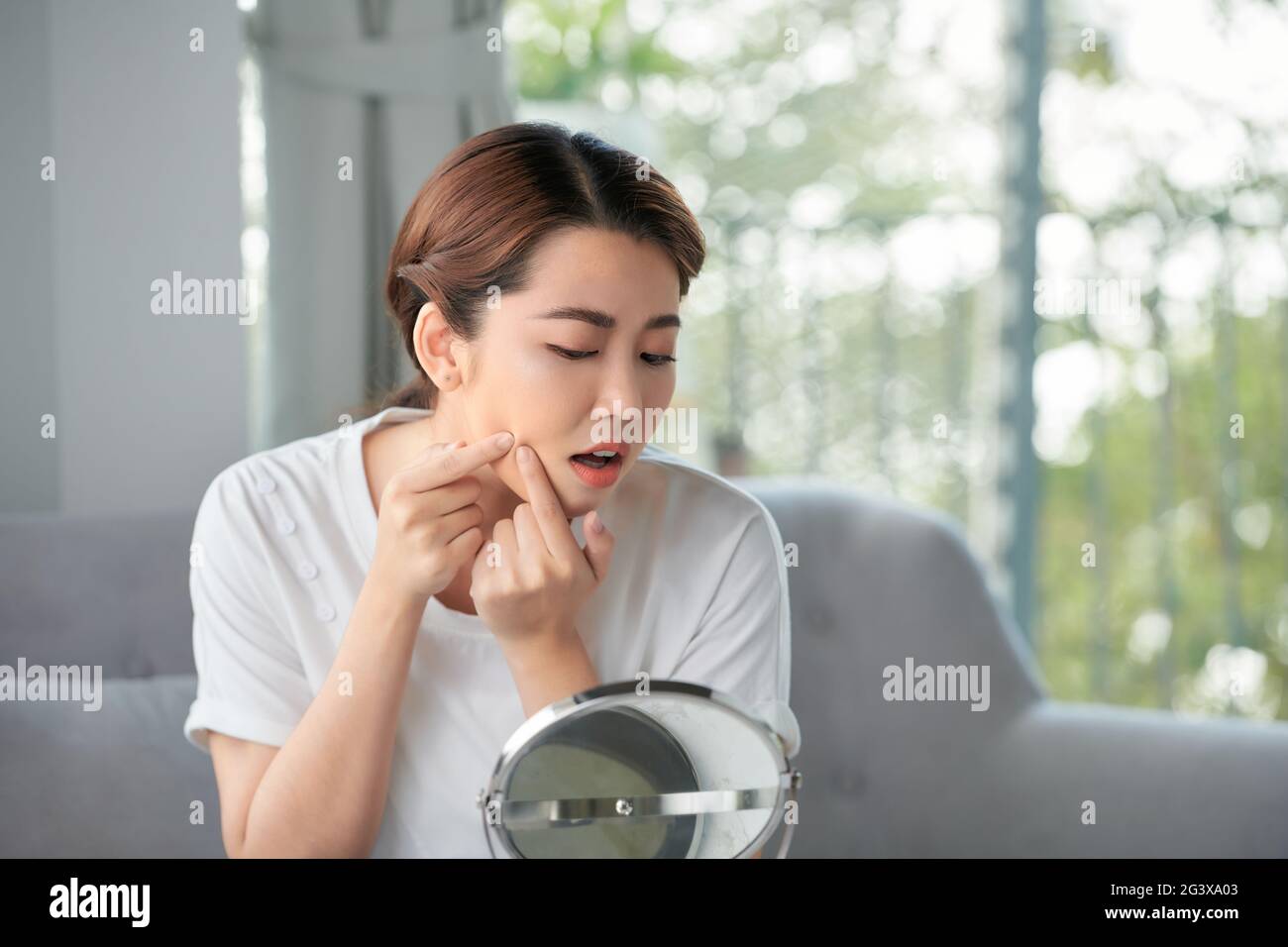 Junge Frau squeeze Ihre Akne vor dem Spiegel Stockfoto