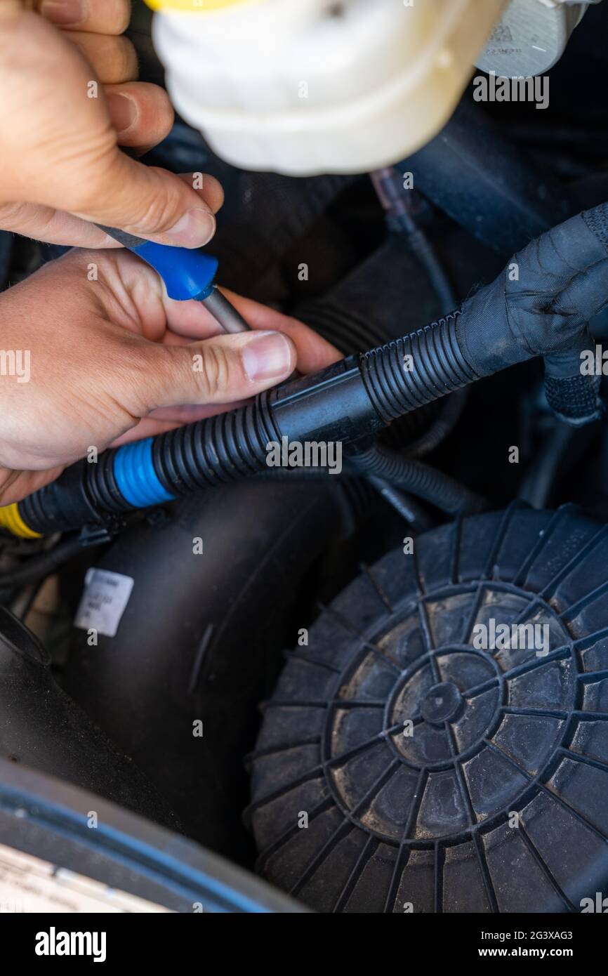 Nahaufnahme der Hände eines kaukasischen Männchens, das entfernt Der Luftfilterdeckel eines Motors Stockfoto