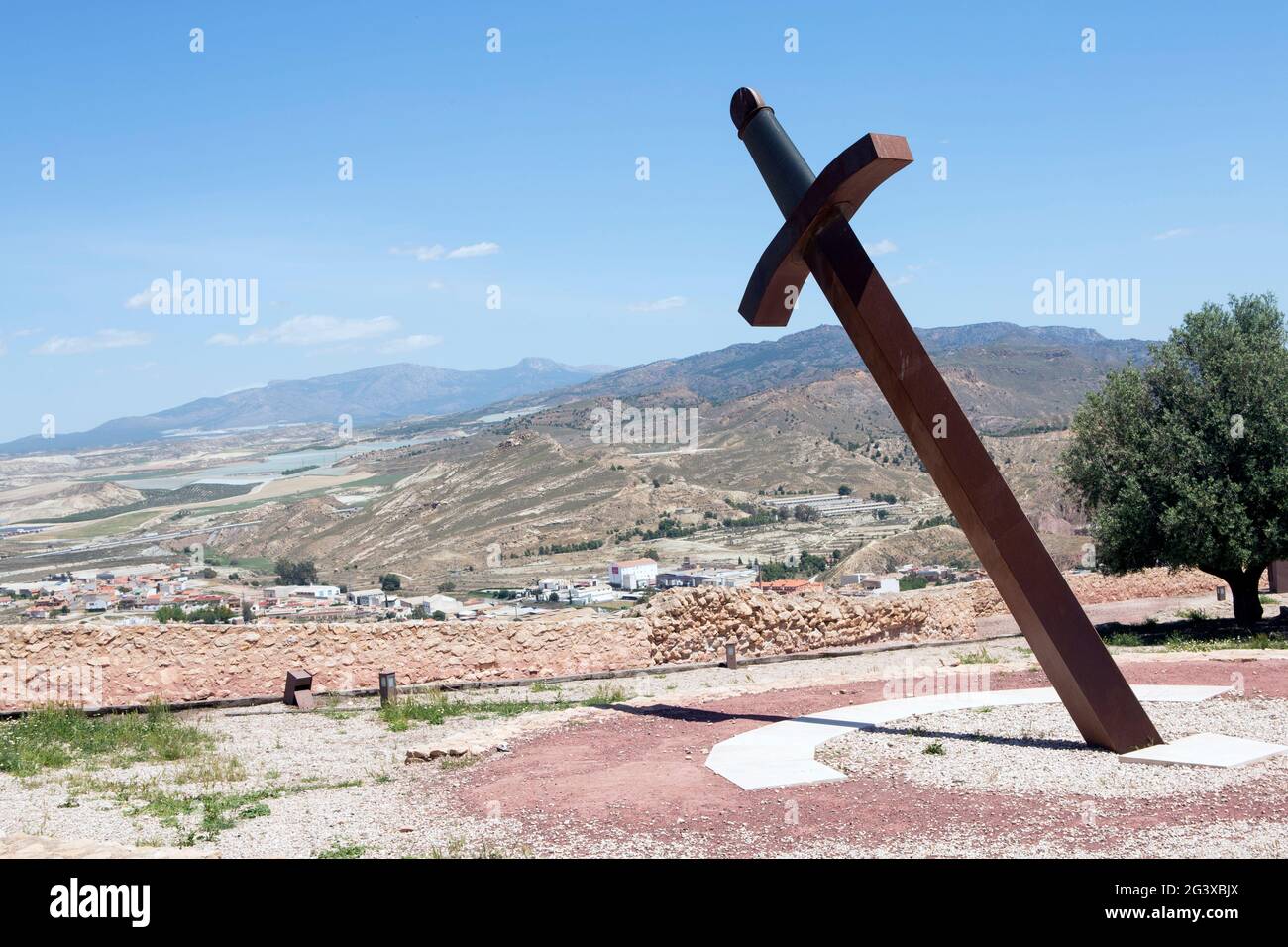 Ein riesiges Eisenschwert, das im Boden stecken blieb, um die Zeit mit dem Schatten (Sonnenuhr) in der mittelalterlichen Burg von Lorca, Murcia, Spanien, zu verschenken. Und mit einem Ventilator Stockfoto