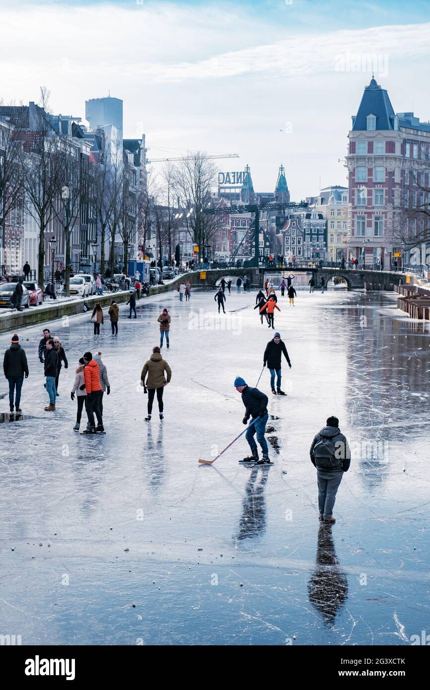 Eislaufen auf den Kanälen in Amsterdam, Niederlande im Winter, gefrorene Kanäle in Amsterdam im Winter Stockfoto