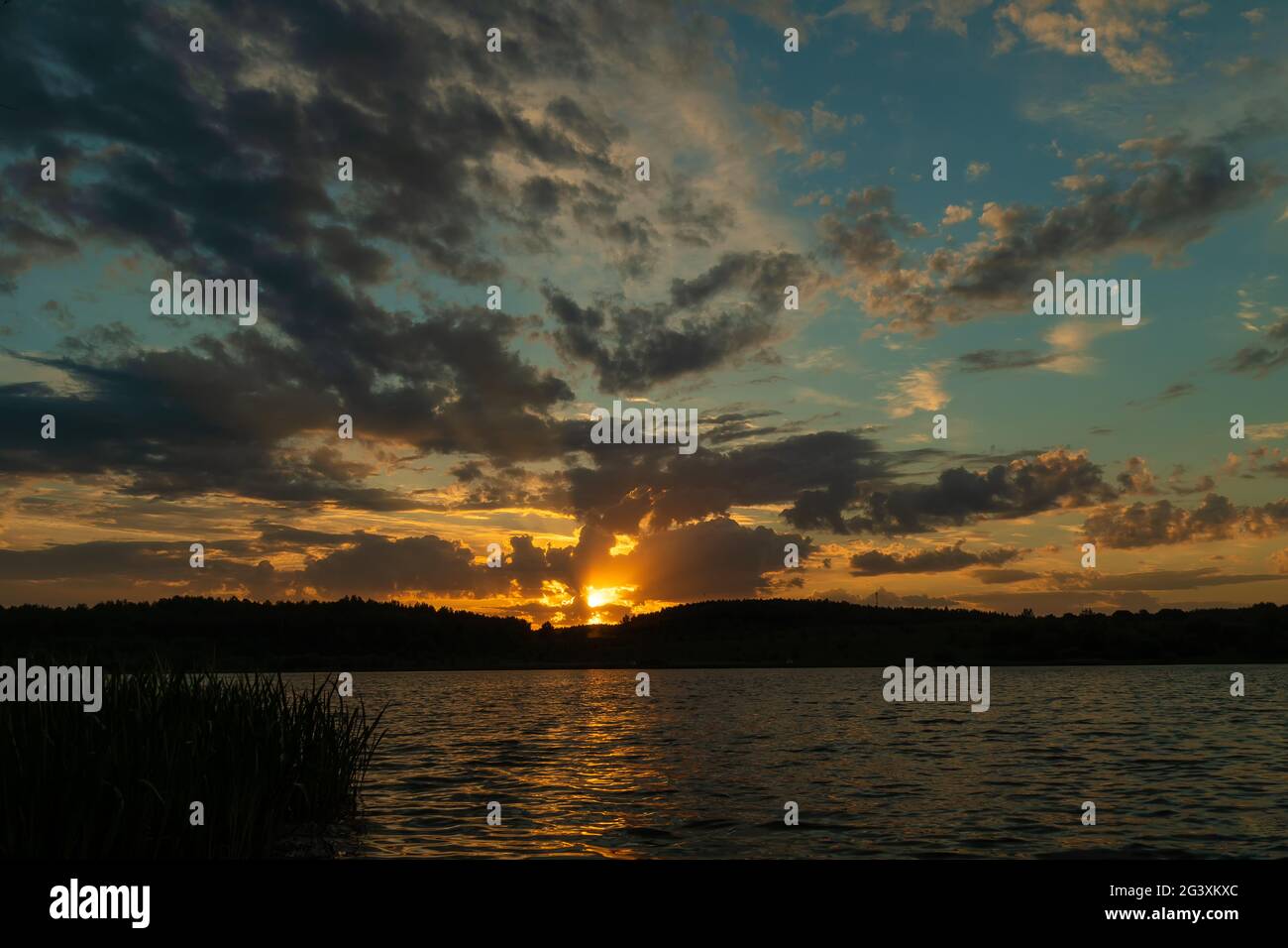 Schöner, herrlicher Sonnenuntergang am See an einem Sommerabend untergeht die Sonne hinter dem Wald. Ein bezaubernder Sonnenuntergang im Sommer mit einem magischen Himmel Stockfoto