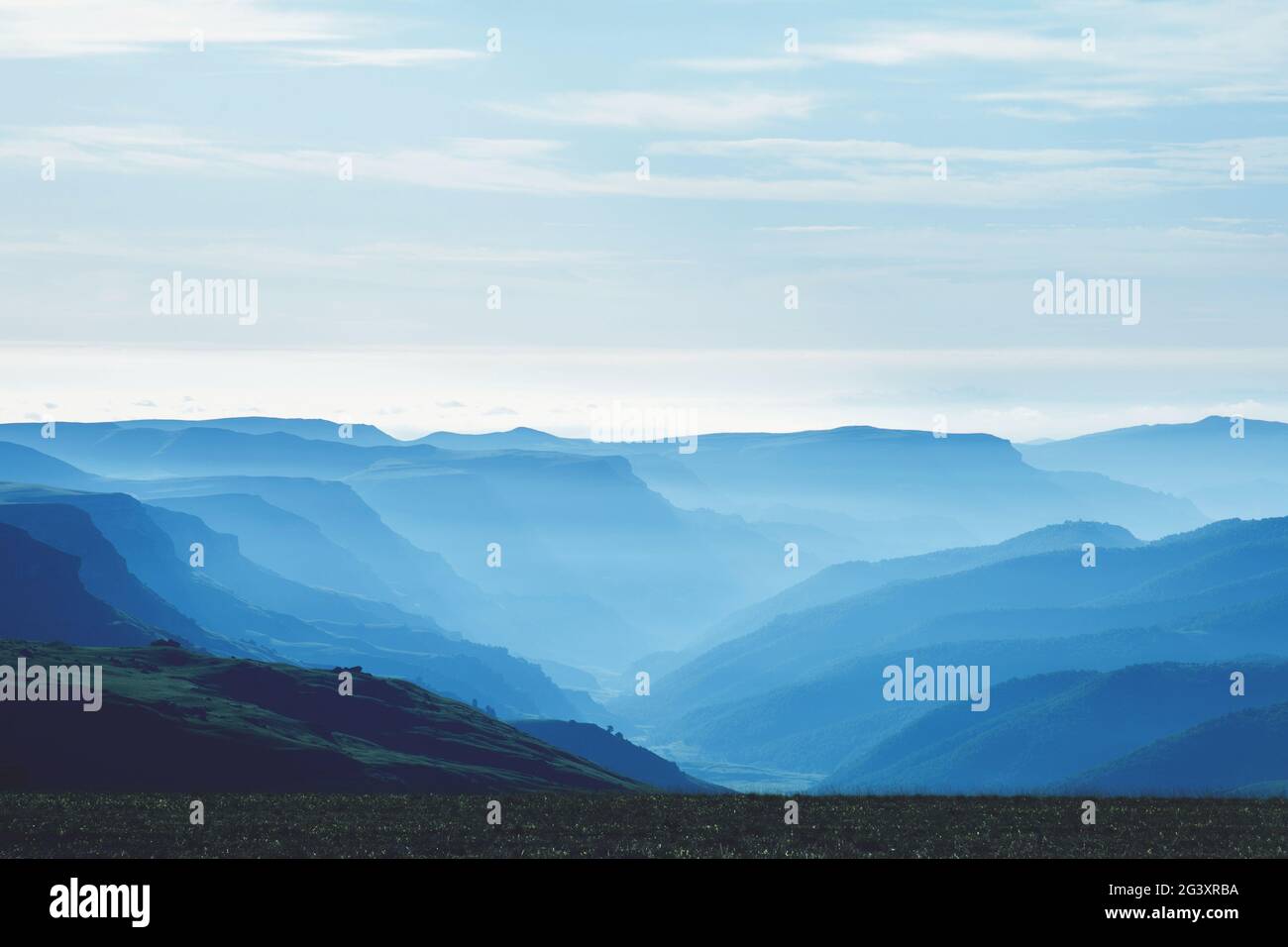 Luftperspektive in den Bergen bei Sonnenaufgang. Dichter blauer Nebel in einem Bergtal, am frühen Morgen flach. Konzept - trave Stockfoto