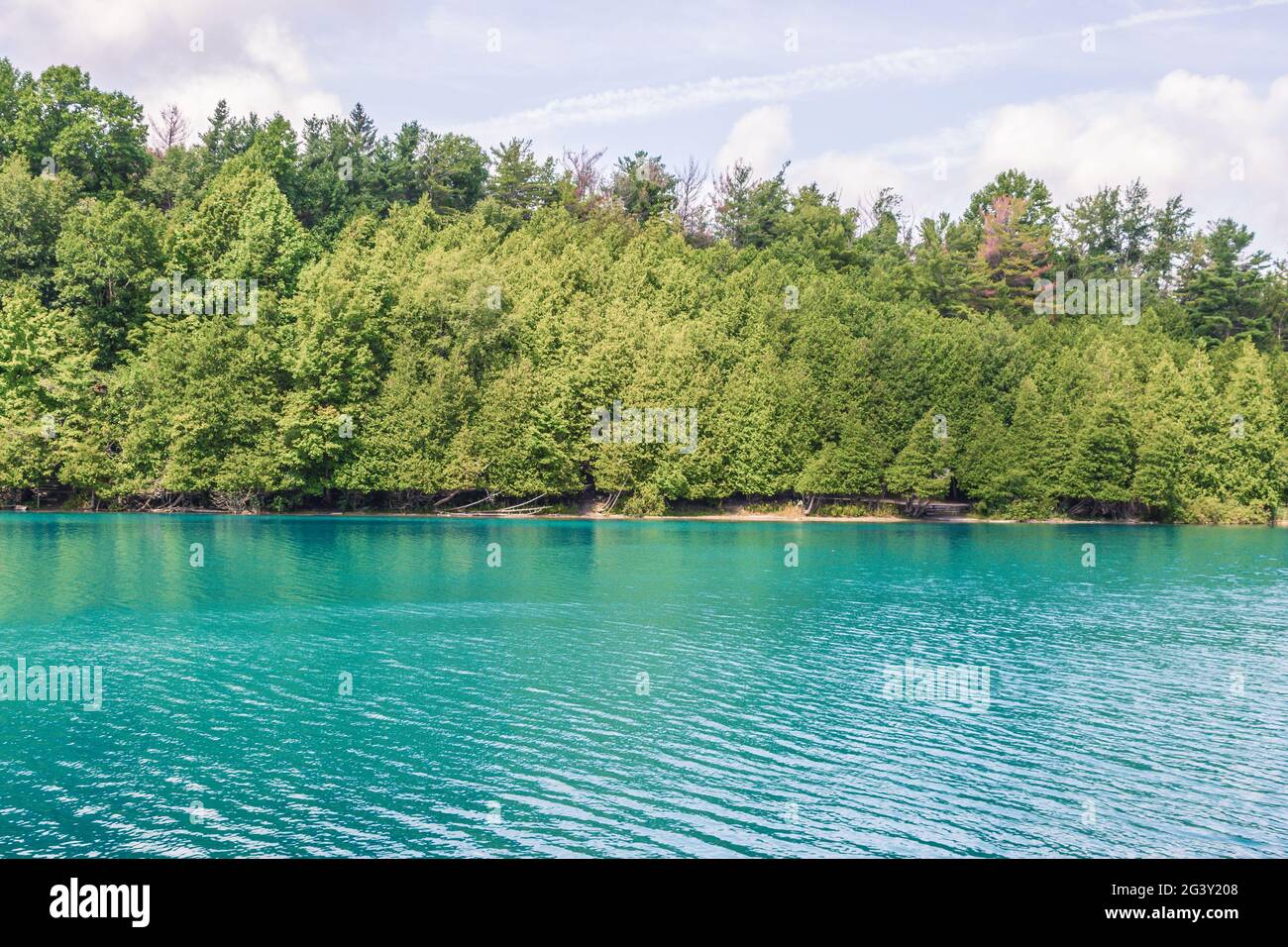 Wunderschöne Seeszene, mit einem von Bäumen gesäumten Ufer und türkisfarbenem Wasser, aufgenommen in Syracuse NY, USA. Stockfoto