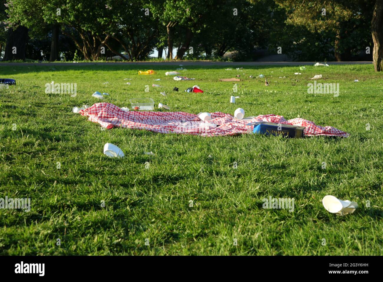 Picknickdecke, Müll und Dreck wurden im öffentlichen Park auf dem ganzen Gras hinterlassen. Kaivopuisto Park, Helsinki, Finnland. 6. Juni 2021. Stockfoto