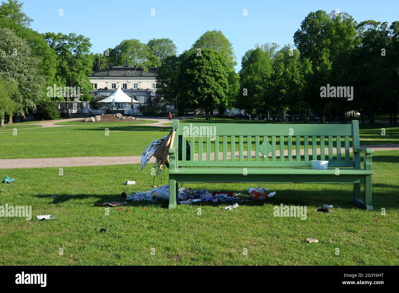 Abfall, Plastiktüten und Chaos, die von einer Parkbank und auf dem Gras hinterlassen wurden. Kaivopuisto Park, Helsinki, Finnland. 6. Juni 2021. Stockfoto