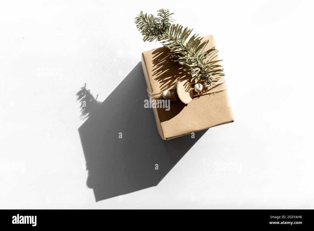 Geschenk in Bastelpapier auf einem weißen mit Schatten isoliert, weihnachten und Null Abfall, umweltfreundliche Verpackung. Ökologisches Weihnachtskonzept, Öko-Dekor Stockfoto