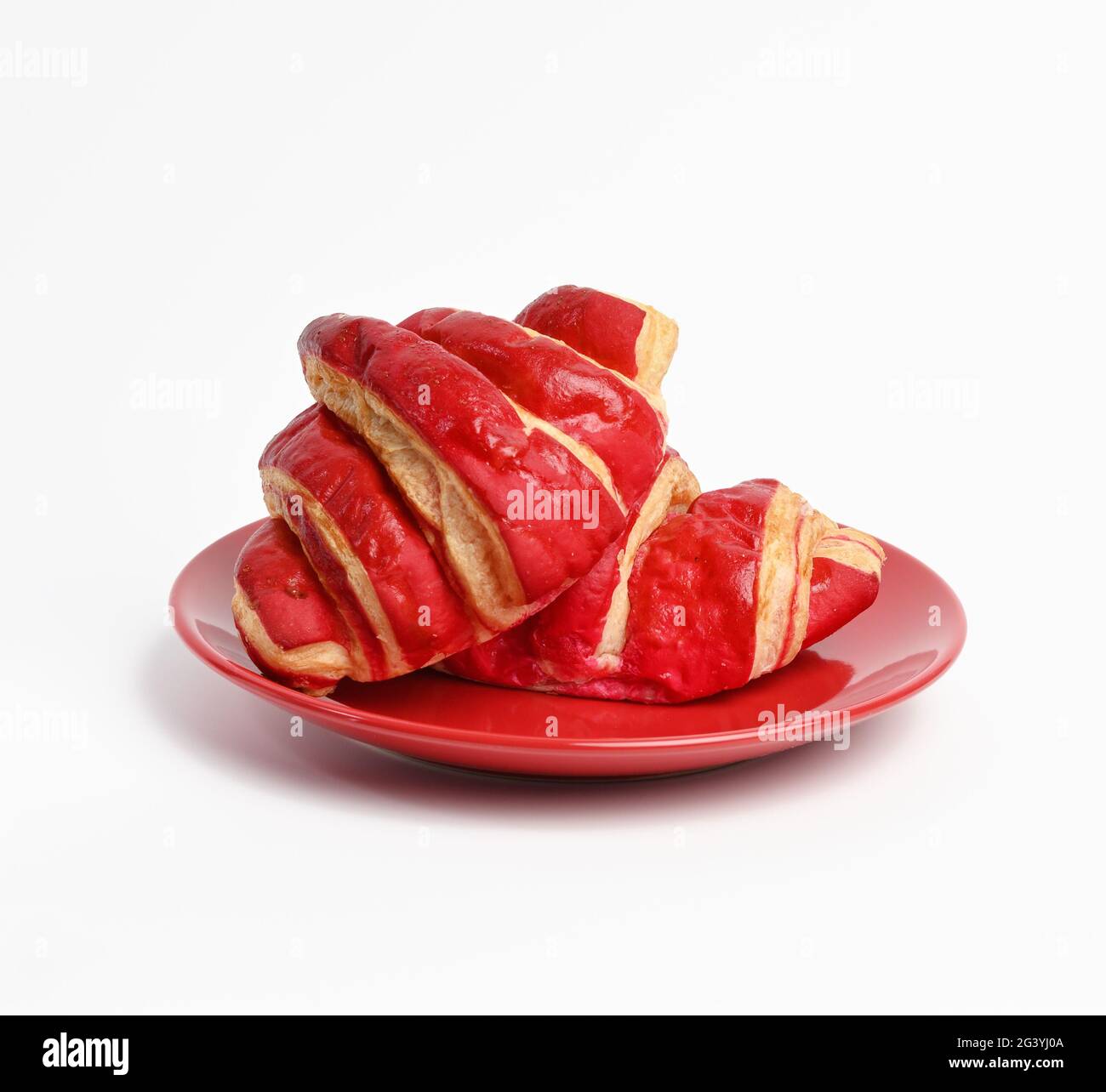 Gebackene Croissants mit Kirschglasur auf einer roten Keramikplatte Stockfoto
