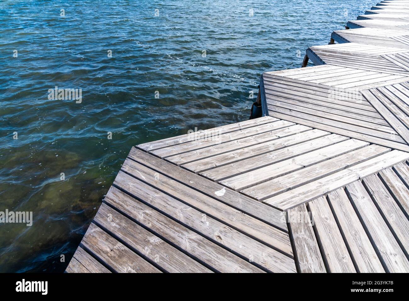 Eine Nahaufnahme aus einem tiefen Winkel abstrakte Ansicht eines Holzes Promenade und Pier, die in den Ozean führen Stockfoto