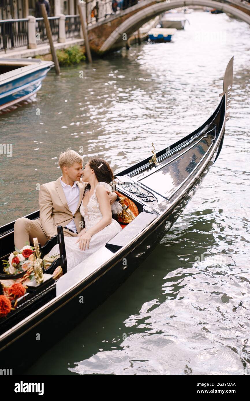 Italien Hochzeit in Venedig. Die Braut und der Bräutigam fahren in einer klassischen Holzgondel entlang eines engen venezianischen Kanals. Nahaufnahme von Streicheleinheiten Stockfoto
