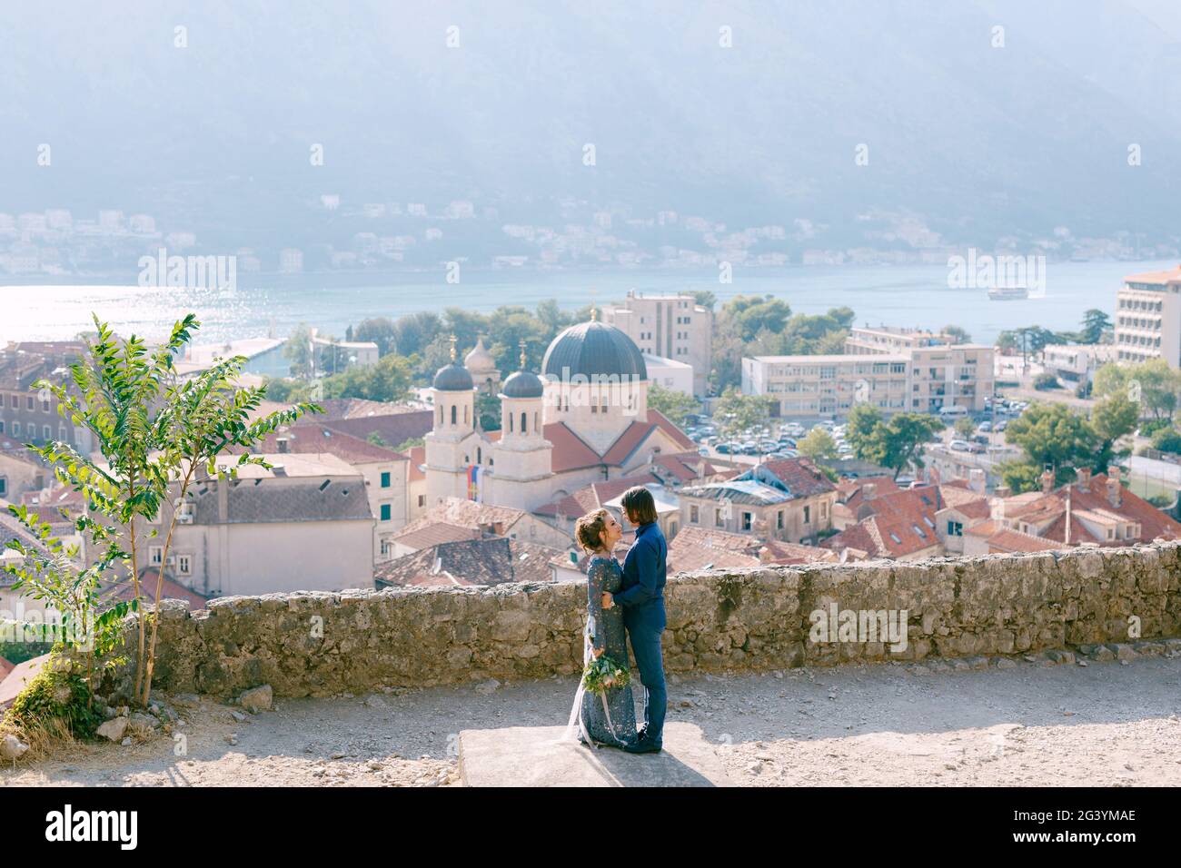 Die Braut und Bräutigam umarmen sich auf der Aussichtsplattform mit Ein malerischer Blick auf die Altstadt von Kotor und Die Bucht von Kotor Stockfoto
