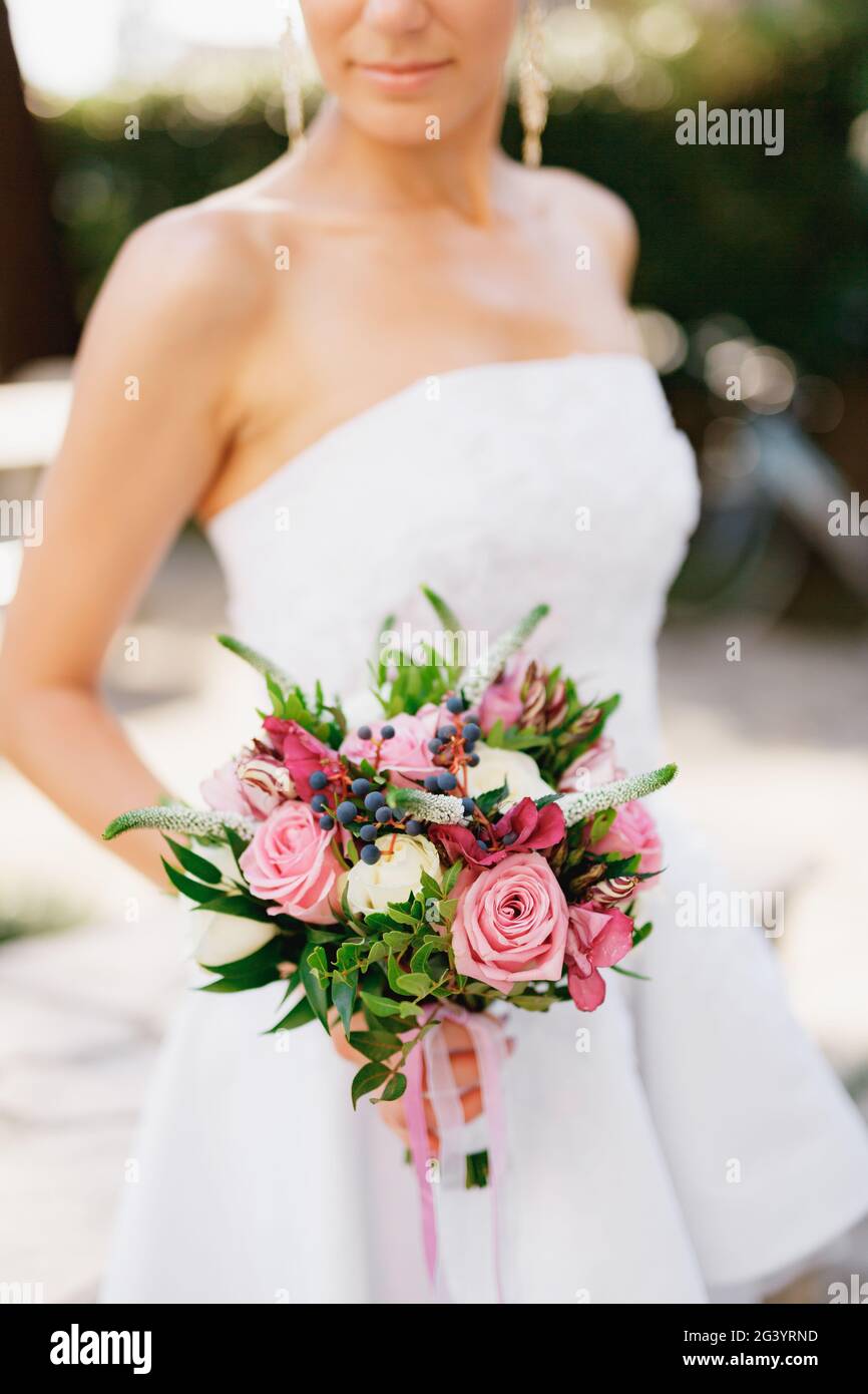 Eine raffinierte Braut, die einen Hochzeitsstrauß mit Rosen, veronica, Viburnum und Buchsbaum in der Hand hält, aus der Nähe Stockfoto