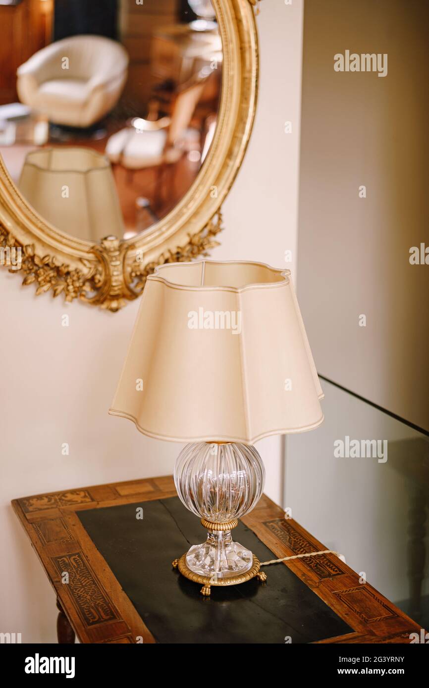 Vintage antike Tischlampe mit weißem Lampenschirm und Kristallsockel.  Antiker Spiegel in einem goldenen Rahmen Stockfotografie - Alamy
