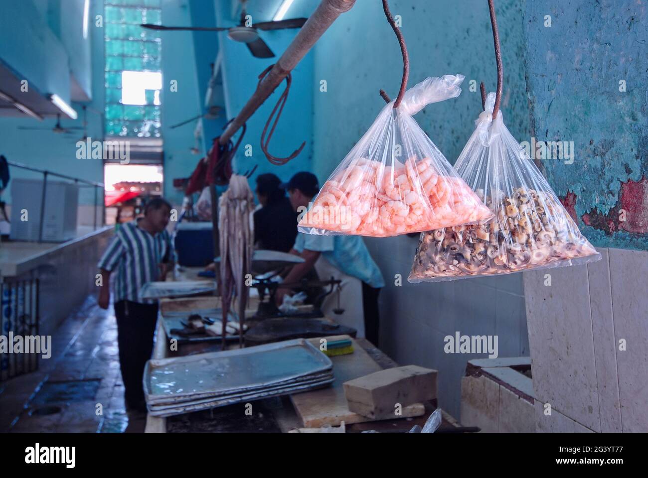 Nahaufnahme von Tüten mit Garnelen und rohem Fisch auf dem städtischen Hallenmarkt in Merida, Mexiko. Im unscharfen Hintergrund Händler und Käufer Stockfoto