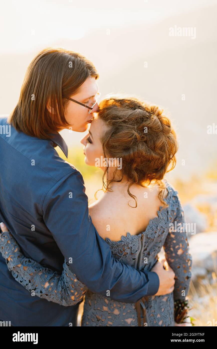 Die Braut und der Bräutigam umarmen sich auf dem Lovcen Berg, der Bräutigam küsst die Braut auf die Stirn, Rückansicht Stockfoto